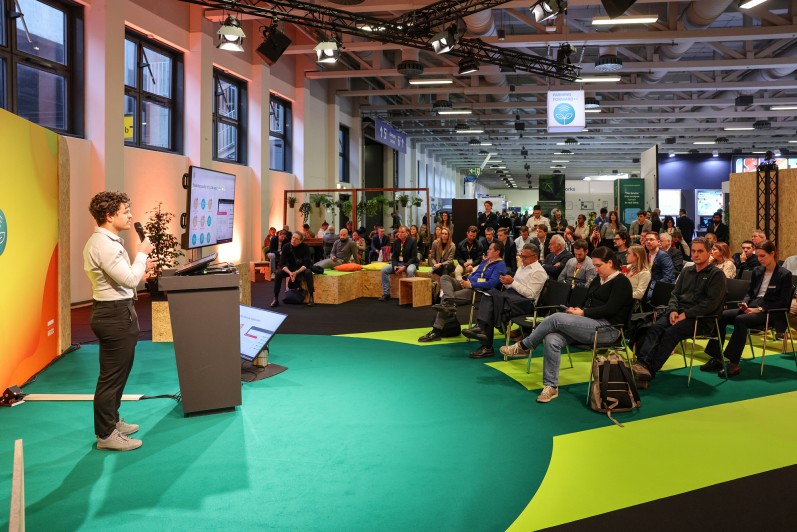 Ein Mann pitcht seine Startup-Idee auf einer Bühne vor Publikum. Ein Mann pitcht seine Startup-Idee auf einer Bühne vor Publikum.