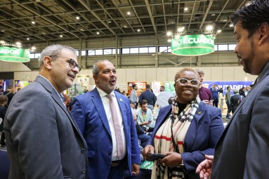 Gruppe von Personen im Gespräch auf einer Messe, im Hintergrund Werbeschilder und Messestände.