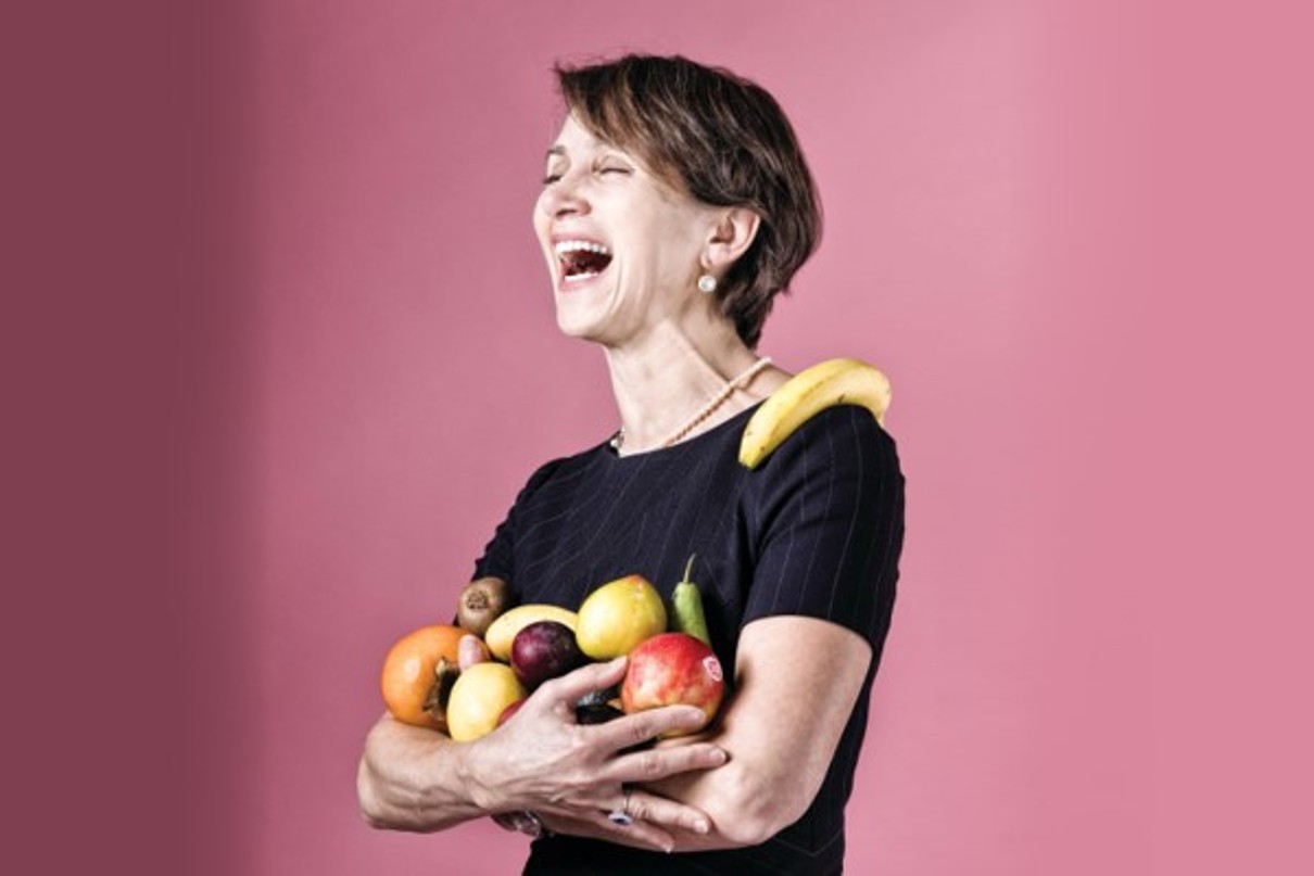 A picture of a woman, Natasha Solano, holding various fruits in her arms.