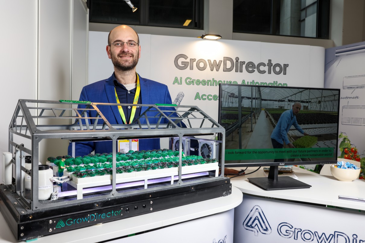 Ein Mann hinter einem kleinen Gewächshaus im Messestand von Grow Director