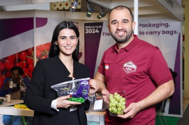 A woman and a man hold grapes in their hands and smile